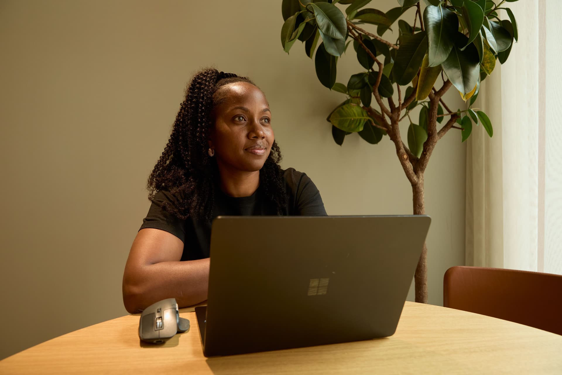 Woman sitting at laptop looking into distance