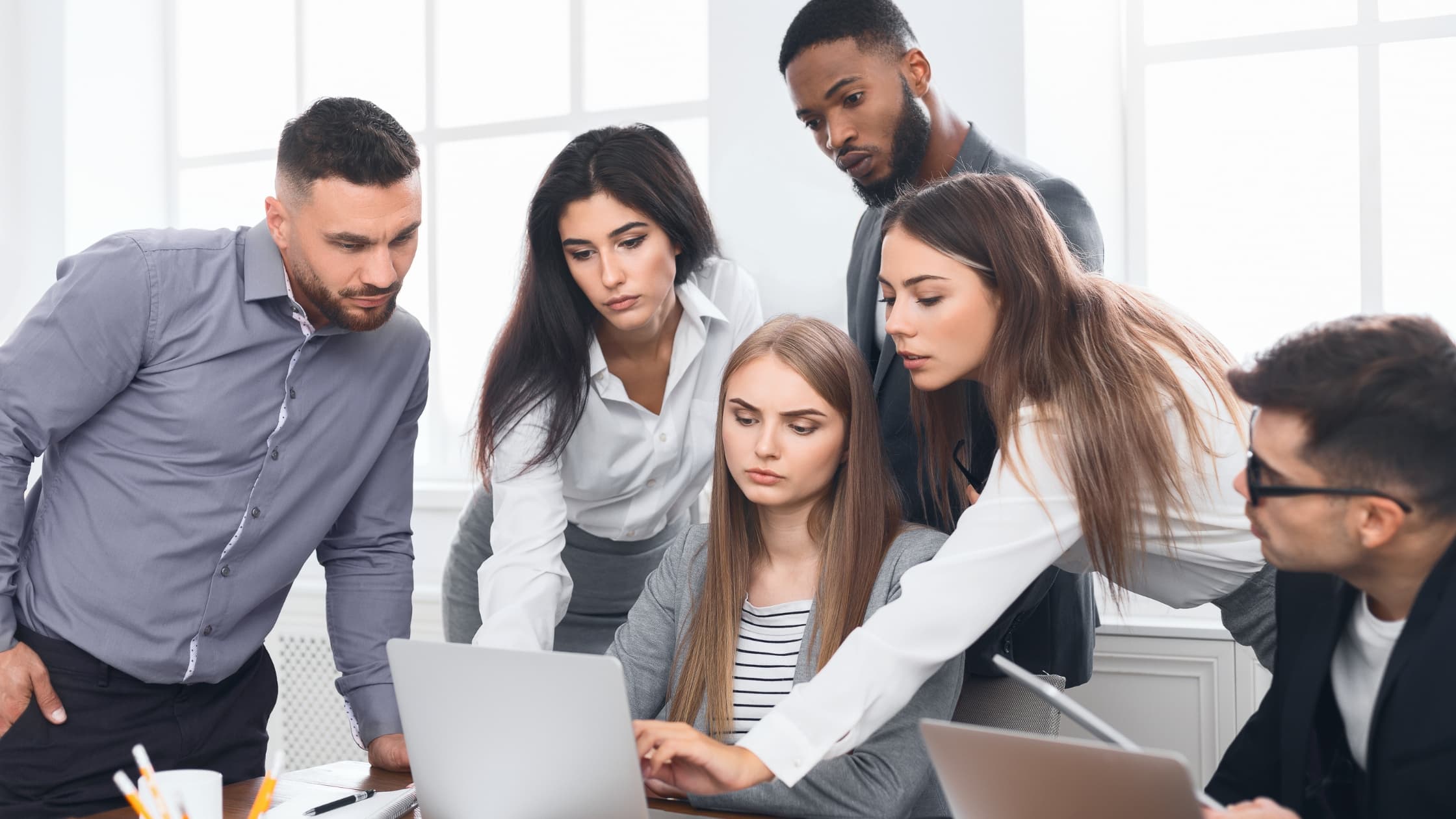 People around a laptop creating an email group in Outlook