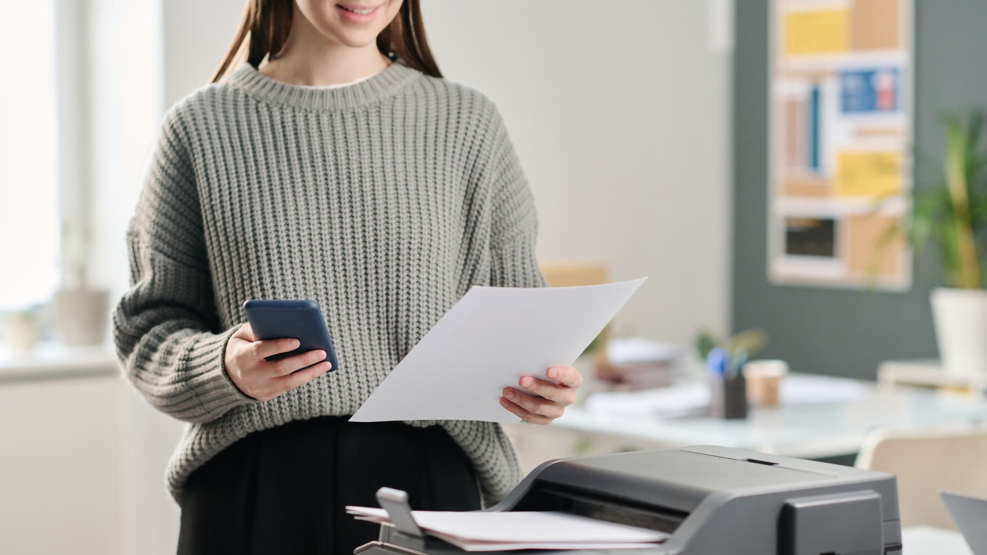 Woman scanning and emailing a document by a printer