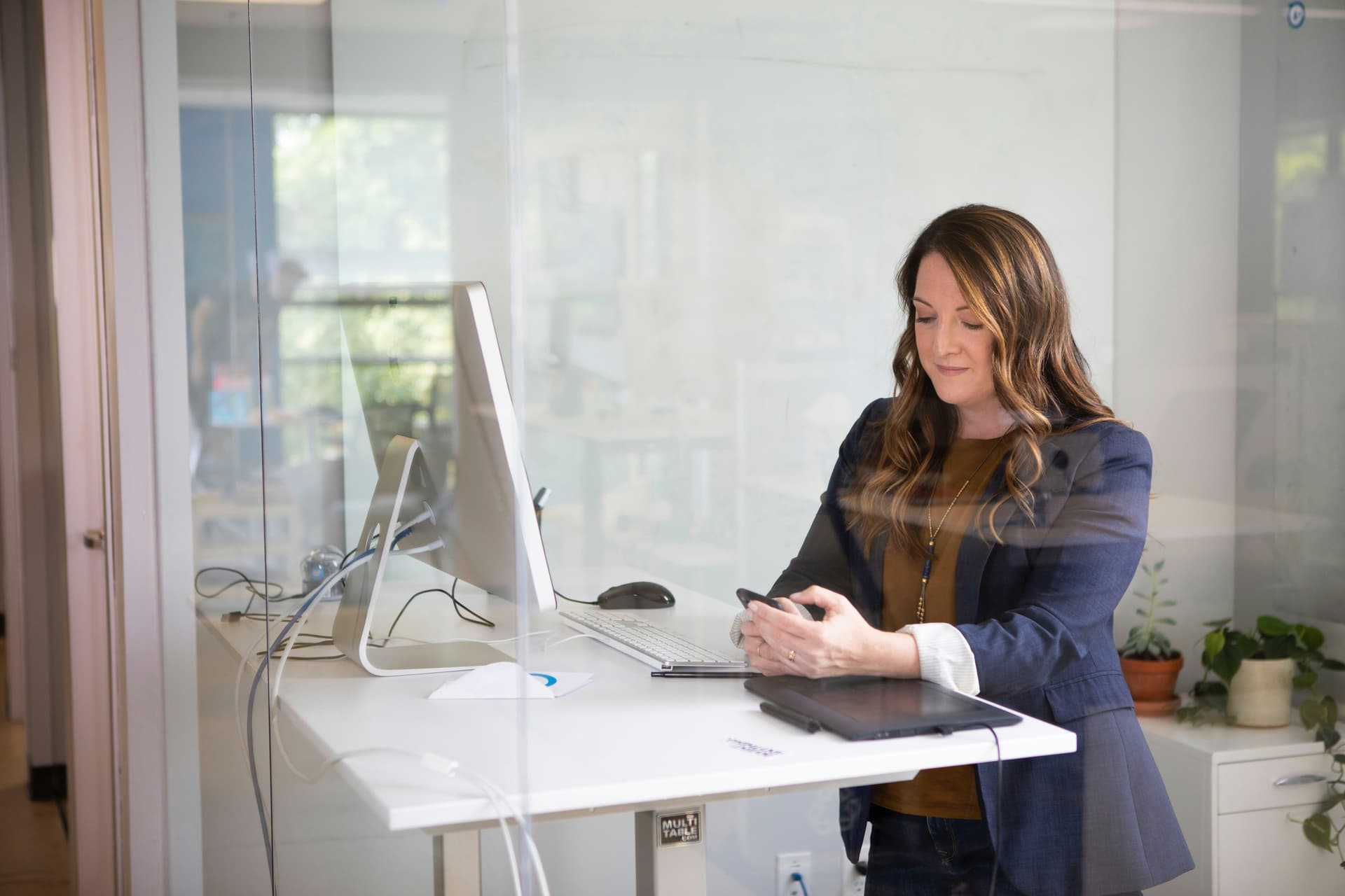 Woman working at desktop computer and using phone