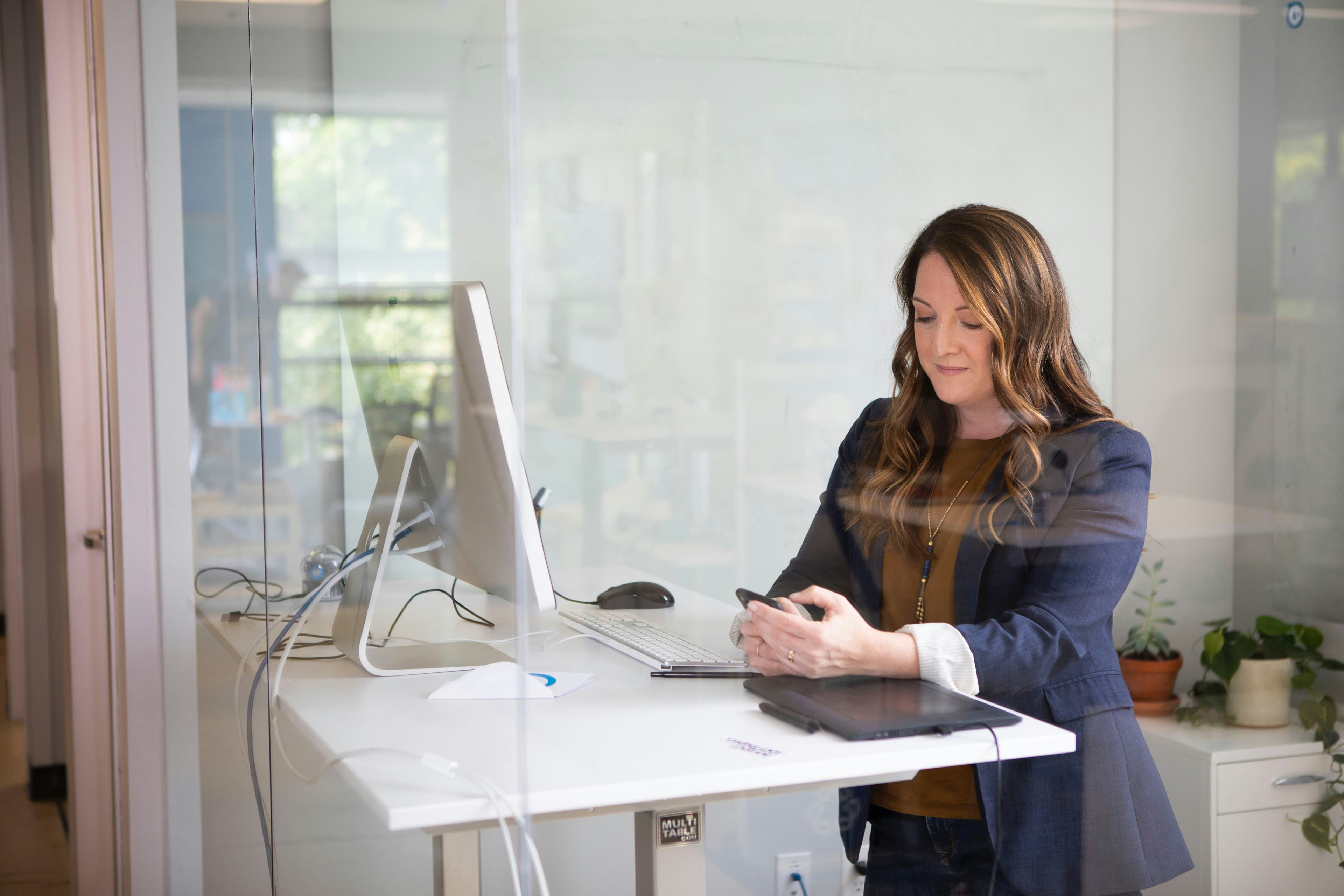 Woman working at desktop computer and using phone